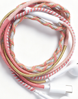 A braided headphone cable with pink, white, and metallic gold threads, featuring white inline controls and USB-C connectors, photographed on a clean white background.