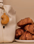 Croissant AirTag® Leather Charm Hanging from Designer Handbag Strap