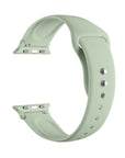 Sage green silicone Apple Watch® band unclasped, flat-lay view showing pin-and-tuck closure and size adapters