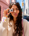 Woman holding mini digital camera with beaded lanyard wristlet outdoors