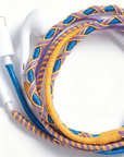 A close-up of white wired earbuds with a thick braided cable in blue, purple, and yellow, arranged on a clean white background.