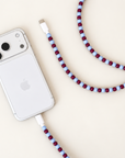 Burgundy and light blue USB-C beaded cable connected to a silver iPhone on cream background