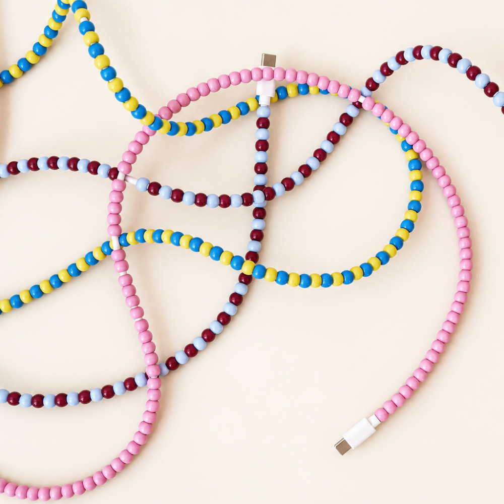 Pink, blue and yellow, and burgundy and light blue USB-C beaded cables laid out on cream background