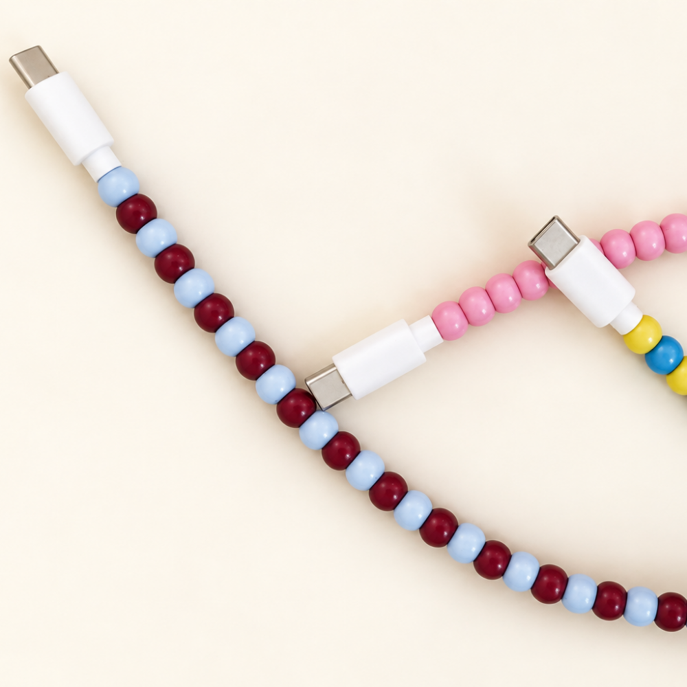 Close-up of burgundy and light blue beaded cable with white USB-C connector beside a pink beaded cable