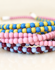Stacked coils of pink, blue and yellow, and burgundy and light blue beaded charging cables