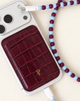 Burgundy and light blue USB-C beaded cable charging an iPhone with a burgundy croc leather magnetic phone wallet