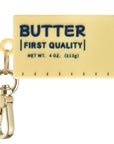 Posh Tech yellow silicone butter-stick bag charm for AirTag with retro First Quality label