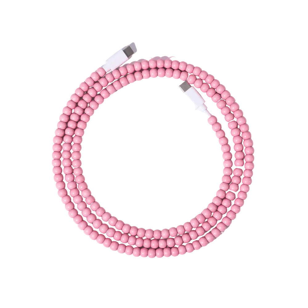 Pink USB-C beaded charging cable coiled on lavender background