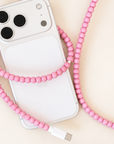 Pink USB-C beaded cable wrapped around an iPhone on cream background
