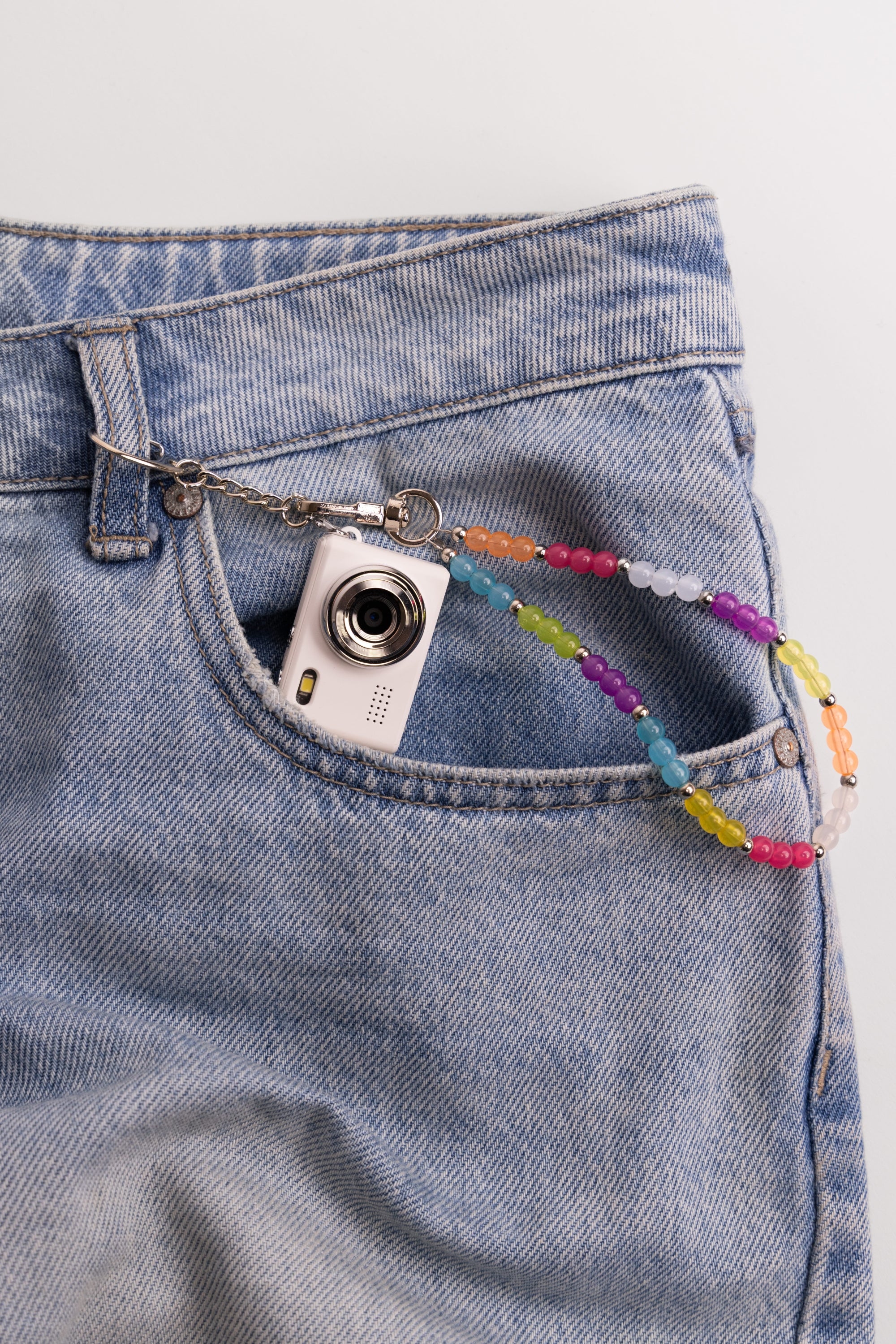 Mini digital camera in jean pocket with rainbow beaded lanyard clip